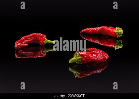 Three red chili peppers on a black background, copy space Stock Photo