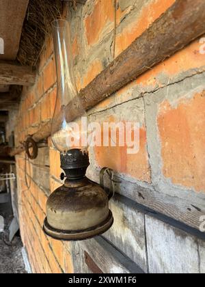 A kerosene lamp hangs on the wall of a brick shed. Stock Photo