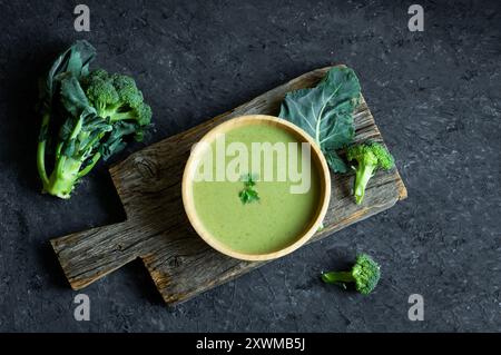 Fresh Broccoli soup in wooden bowl on dark table, diet detox food concept, top view Stock Photo