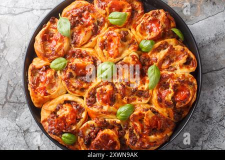 Homemade Pizza swirl Rolls with italian sausages, Mozzarella and basil closeup on the bakong dish on the table. Horizontal top view from above Stock Photo