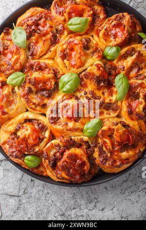 Cheesy pepperoni pizza rolls with italian sausages, Mozzarella and basil closeup on the bakong dish on the table. Vertical top view from above Stock Photo