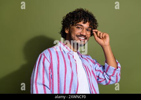 Portrait photo of attractive mexican it specialist in striped shirt touching trendy glasses posing isolated on khaki color background Stock Photo