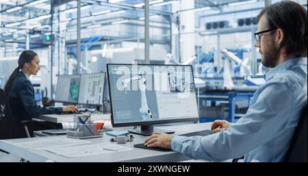 Young Asian Electronics Engineer and Automation System Administrator Working on Desktop Computers in Office. Specialists Monitoring, Analyzing Conditions at a Modern Components Manufacturing Plant Stock Photo
