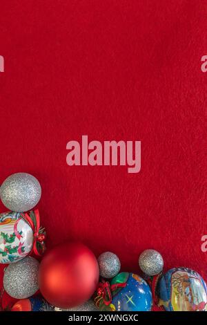 A Christmas flat lay featuring ornaments at the bottom of a red fabric background, with empty space for text. Ideal for holiday designs, greeting card Stock Photo