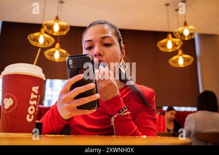 London - 06 11 2022: Girl puts lipstick on her lips in a club Stock Photo