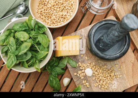 Overhead view of basil, parmesan, pine nuts and olive oil on a table for making fresh basil pesto sauce Stock Photo