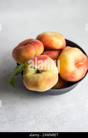 Close-up of a bowl of ripe flat peaches on a table Stock Photo