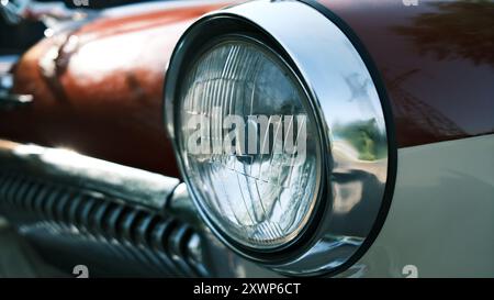 Vintage car headlight close-up. Classic automobile front light detail. Retro vehicle chrome trim and glass lens design element Stock Photo