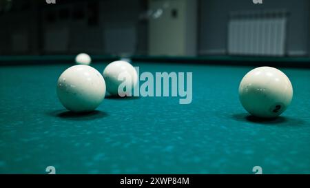 white billiard balls on green felt table. Close-up of cue ball, pool game equipment, sports and recreation theme. Stock Photo