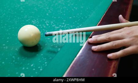 Player aiming cue stick at white ball on pool table. Close-up of billiards game in action, sports and leisure activity Stock Photo