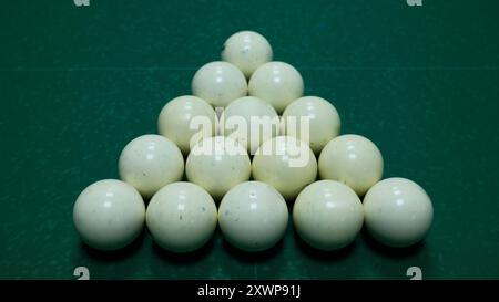 Billiard balls arranged in triangle shape on green felt table. Snooker or pool game setup, sports and leisure concept. Stock Photo