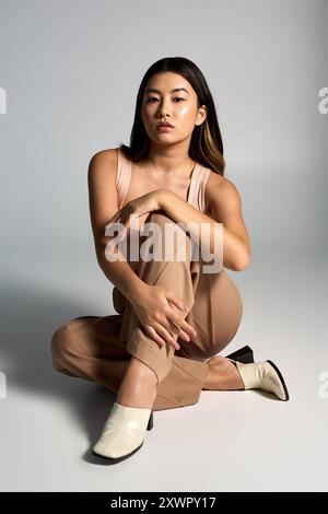 A confident woman sits with her legs crossed, wearing a stylish outfit. Stock Photo