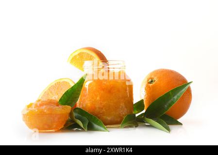 Jar of orange jam isolated on white background with fruit around it reflected in the base. Front view. Stock Photo