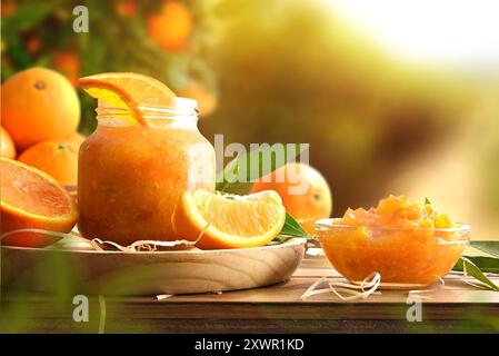 Homemade orange marmalade in glass jars on wooden table and nature background. Front view. Stock Photo