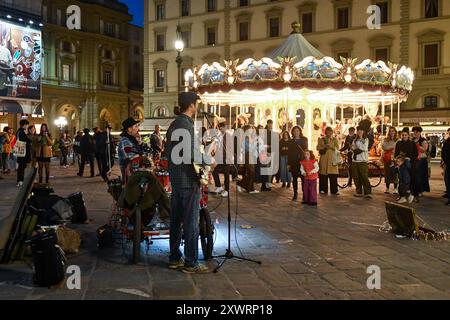 Street musicians playing in front of the old illuminated carousel in Piazza della Repubblica at night, Florence, Tuscany, Italy Stock Photo