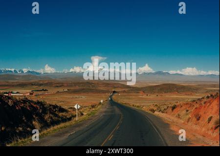 the road through the red desert against a backdrop of snowy mountains. High quality photo Stock Photo