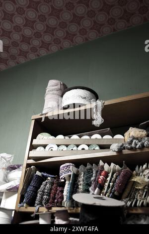 Wooden shelf stocked with various textile rolls and trims, showcasing a colorful assortment. Ideal for concepts such as creativity, craftsmanship, and textile art. Represents the beauty of diverse textures coming together. Stock Photo