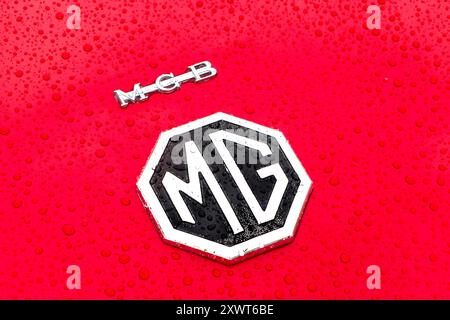 Close-up of the MG logo on a red car with water droplets on the surface. MGB Stock Photo