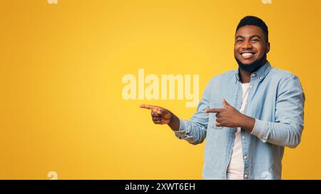 Cheerful black guy pointing two fingers aside at copy space Stock Photo