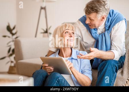 Modern senior spouses using digital tablet together Stock Photo