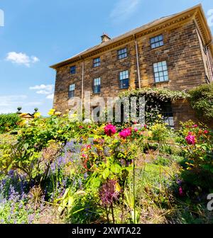 Ormesby Hall - Middlesbrough Beautiful historic brick house with a lush garden in the foreground, showcasing vibrant flowers and green foliage Stock Photo