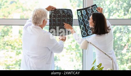 Doctors examining x-ray scans in medical office near window Stock Photo