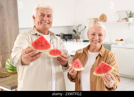 Mature couple with slices of watermelon in kitchen Stock Photo