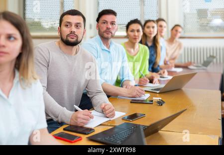 Group of attentive students writes synopsis in copybooks Stock Photo