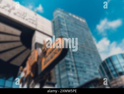 A blurred, abstract image of an urban environment in Shenzhen, China, featuring a tall glass building and a blue sky with bokeh background. Stock Photo