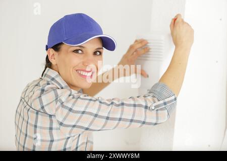 female technician installing security system near door wall Stock Photo