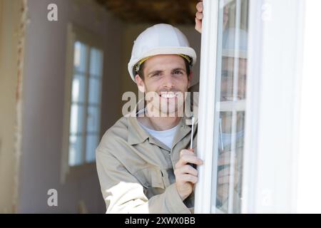 male builder with a screwdriver sets fittings on the window Stock Photo