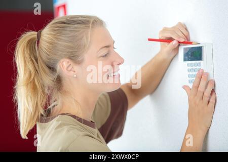 happy female technician installing security system Stock Photo