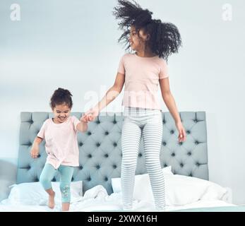 Happy family, siblings and jumping in bedroom with children, bonding and having fun on weekend in home. People, excited and kids for joy, connection Stock Photo