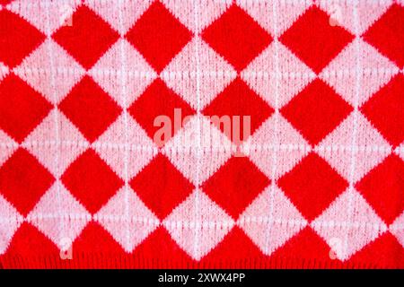 A close-up of a vibrant red and white checkered knitted fabric, showcasing a classic argyle pattern. The textured material evokes a sense of warmth an Stock Photo