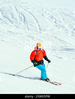 Man in red jacket blue pants ski downhill in ski resort slope Stock Photo
