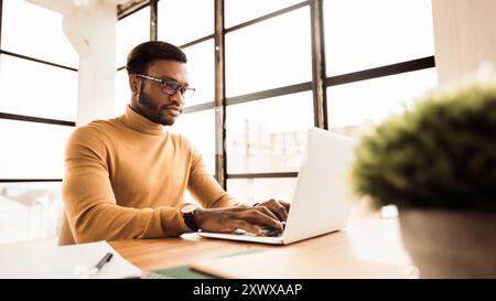 Afro man working on laptop in modern office Stock Photo