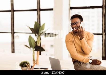 Black guy talking on phone sitting on the table Stock Photo