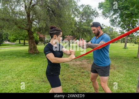 Fitness enthusiasts practicing resistance band exercises in a scenic outdoor environment, utilizing nature for their strength training session in a pa Stock Photo