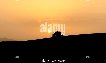 Silhouette of unidentified muslim Berber man praying on sand dunes at ...