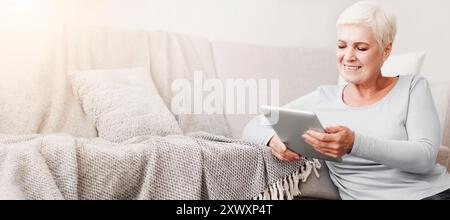 Happy old woman using digital tablet at home Stock Photo