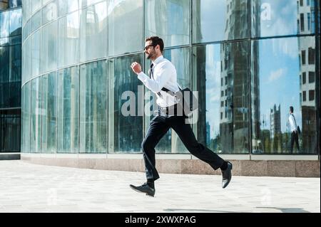 Hurrying to work. Full length of young businessman looking forward while running along the street Stock Photo