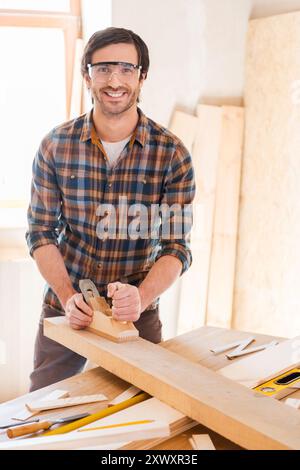 Skilled carpenter. Cheerful young male carpenter working with wood in his workshop Stock Photo
