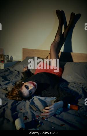 A woman in a chic, grungy outfit poses on a bed. Stock Photo