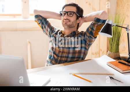 My space for inspiration.Handsome young man holding head in hands while sitting at his working place Stock Photo