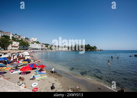 Ulcinj, Montenegro - 13 July 2024: Scenic view of a crowded beach with people sunbathing and swimming. Colorful umbrellas add vibrancy to the serene c Stock Photo