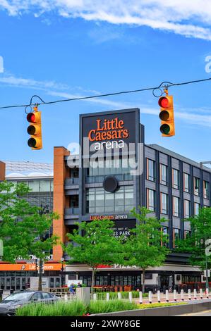 Detroit, USA - August 1, 2024: Exterior architecture and sign at Little Caesars Arena. The building is framed in two stoplights. Stock Photo