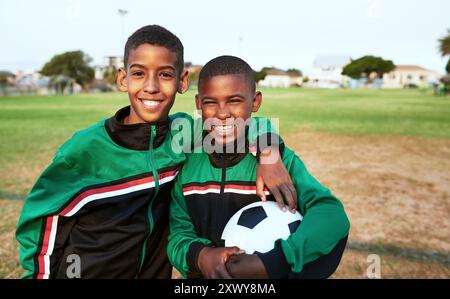 Happy boys, portrait and hug with soccer ball for sports, match or team game together on grass field. Young male person, athlete or football players Stock Photo