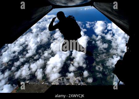 At 12,000 feet, a U.S. Navy SEAL (Sea Air Land) salutes as he exits a C-2 Carrier Onboard Delivery (COD) aircraft from Fleet Logistics Squadron Three Zero (VRC-30) Detachment Five, during parachute training over Andersen Air Force Base, Guam.  U.S. Navy photo by Photographer’s Mate 1st Class Chris Desmond. AIR FORCE BASE, GUAM (January 11, 2000). Stock Photo