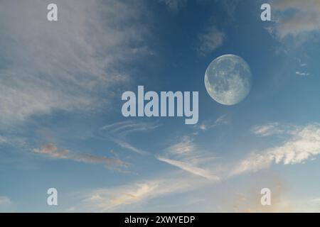 Highly detailed bright full moon in the twilight or night cloudy blue sky. Copy space abstract background. Stock Photo