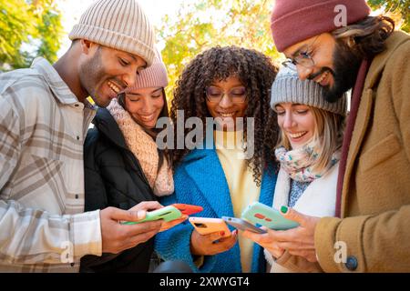 Cheerful group of young friends using cell phones outdoors. Stock Photo
